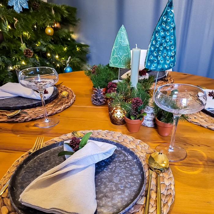gedekte kersttafel met een kerstboom op de achtergrond